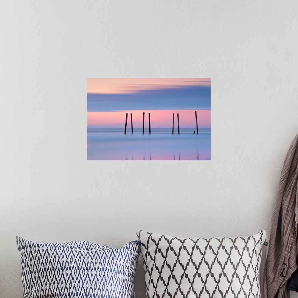 A bohemian room featuring Silhouettes of seven pilings in the ocean at sunset in New Jersey.