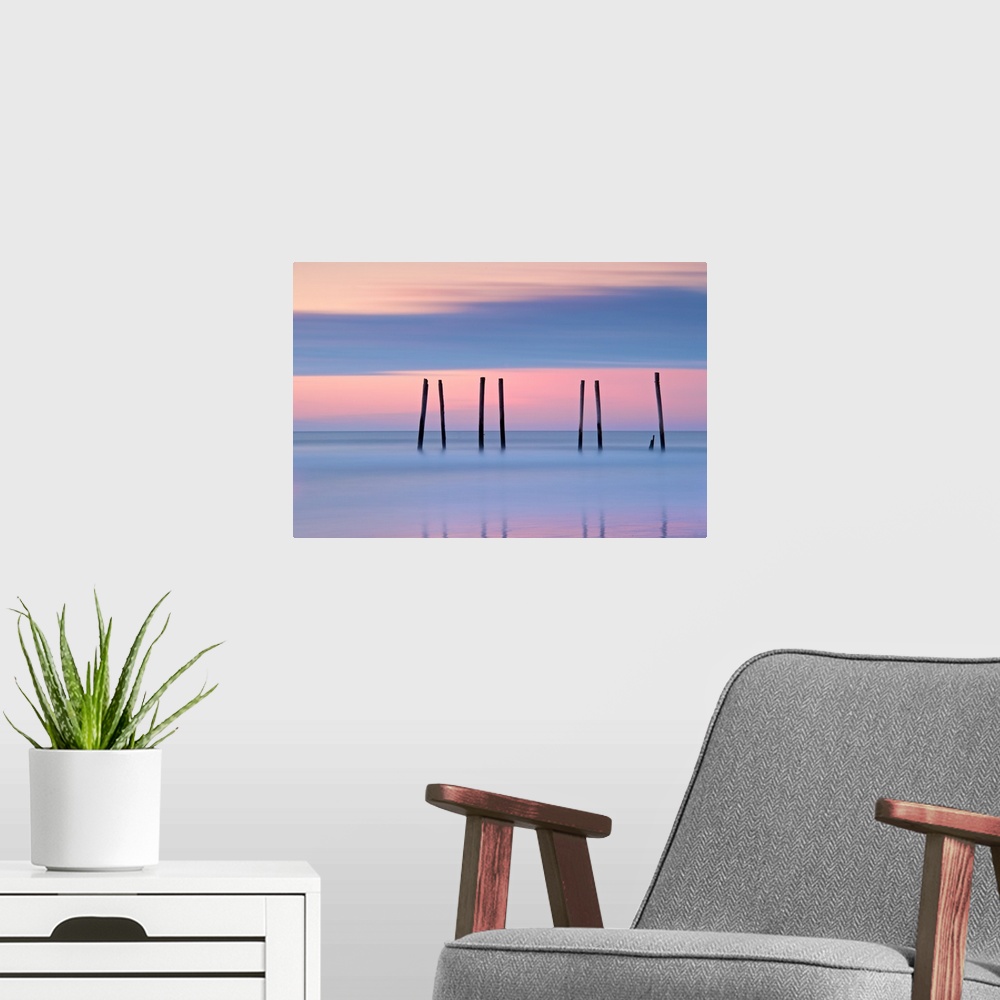 A modern room featuring Silhouettes of seven pilings in the ocean at sunset in New Jersey.
