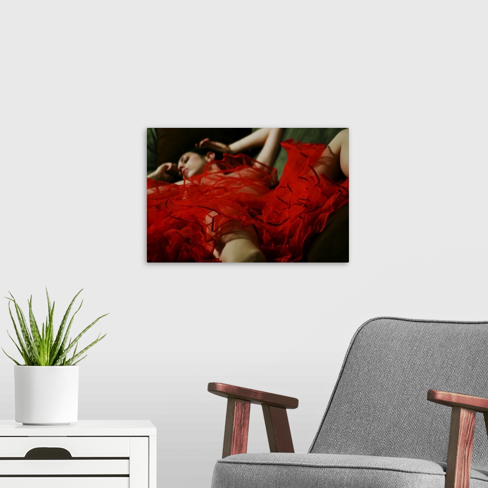 A modern room featuring A naked woman lying under a red piece of material
