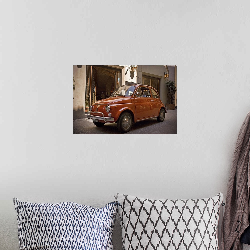 A bohemian room featuring A small red car drives through the narrow streets in the downtown area of an Italian city.