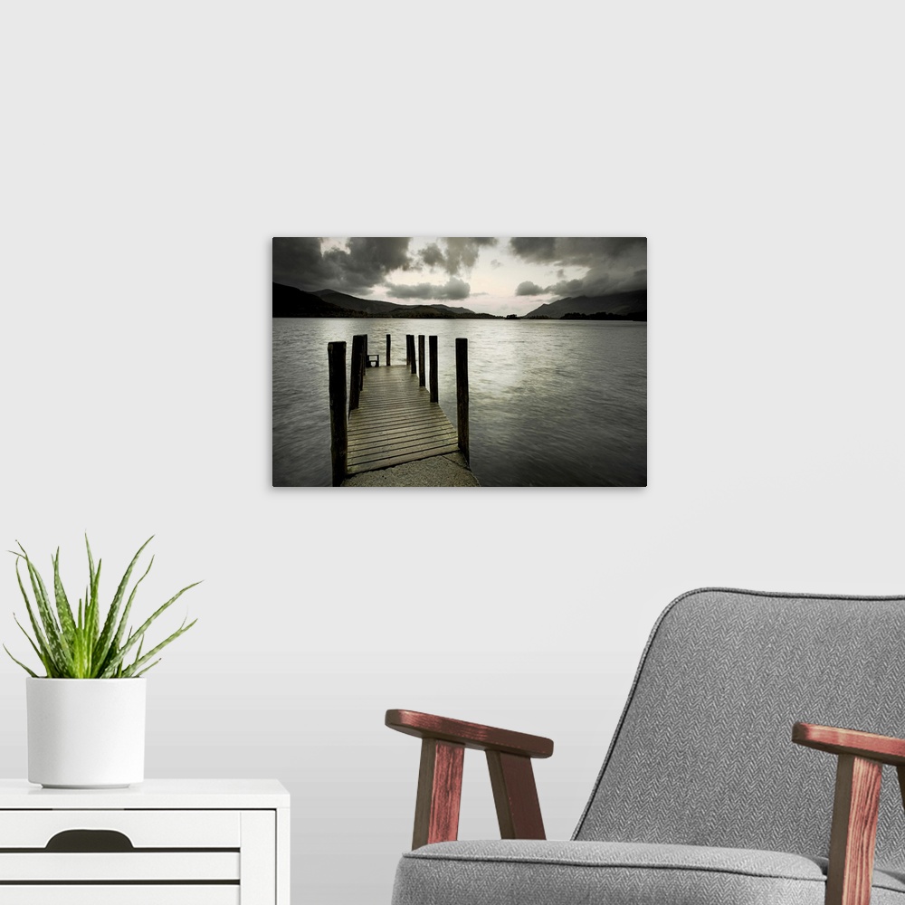 A modern room featuring A small wooden jetty looking out over a lake with stormy clouds over a dark headland