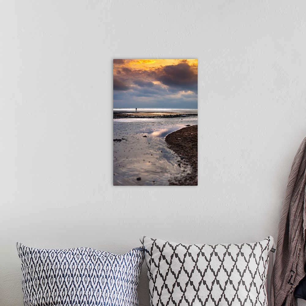 A bohemian room featuring A lone figure walking on an empty beach in winter with storm clouds above a calm sea.