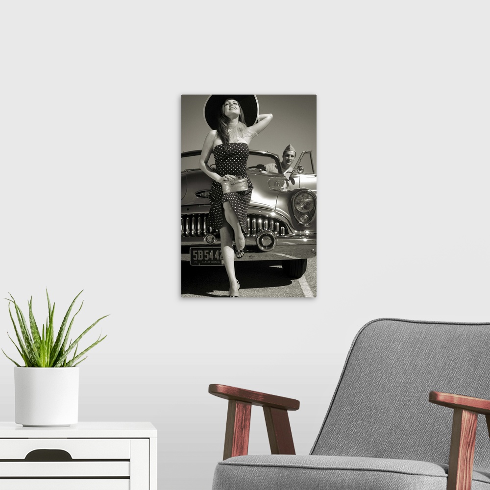 A modern room featuring A model wearing a large hat and a spotted dress with a 50's car