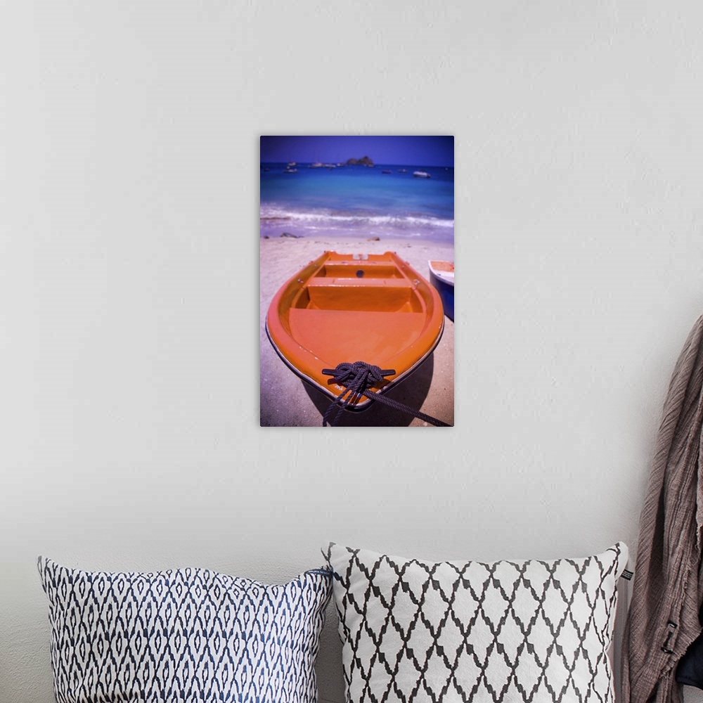 A bohemian room featuring An colorful orange row boat on a Caribbean beach in front of the turqoise Caribbean Sea.