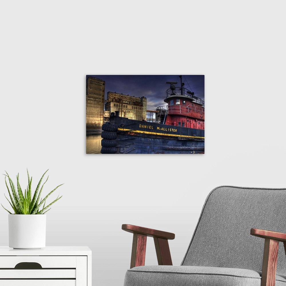 A modern room featuring An old tug boat near to industrial buildings