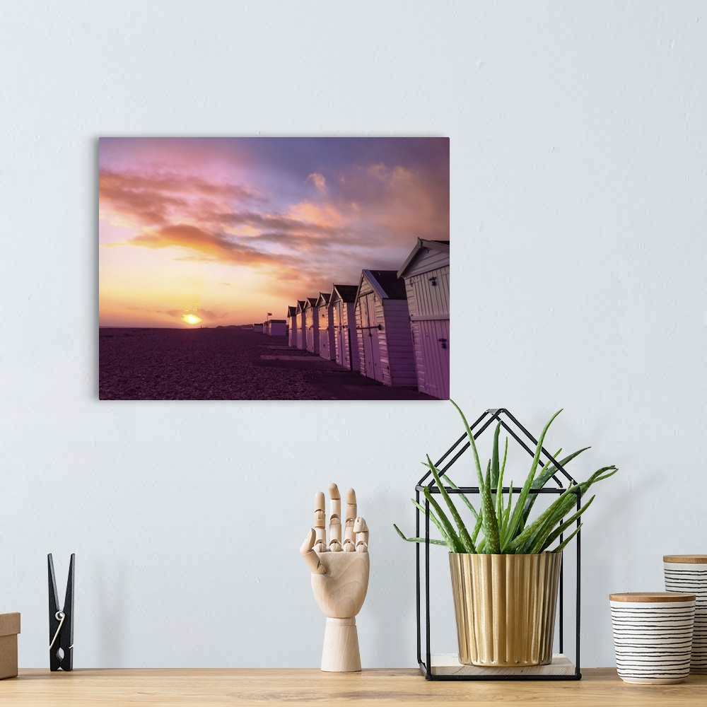 A bohemian room featuring The sun setting over a Sussex beach with a purple sky.