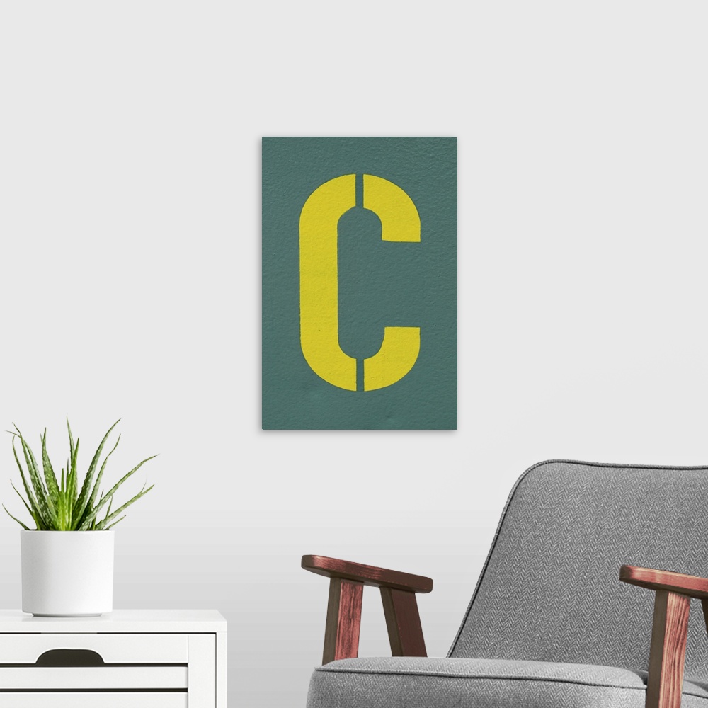 A modern room featuring Yellow letter C sprayed on a greyish, green wall.