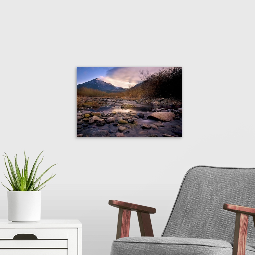 A modern room featuring A rocky river overlooking a mountain at sunset.