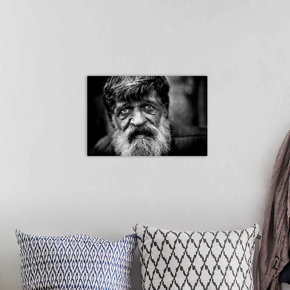 A bohemian room featuring Close up of a mans face with a grey beard and tired eyes