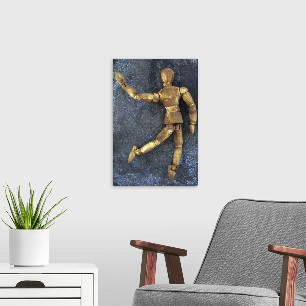 A modern room featuring Dark stained wooden mannequin lying on tarnished metal sheet as if running skipping dancing or wa...