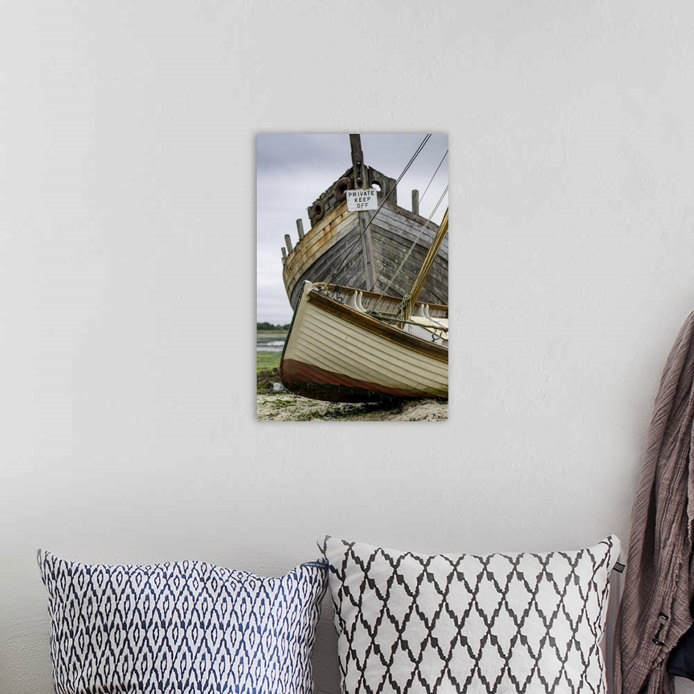 A bohemian room featuring A small sailing dinghy beside a large rotting hulk of a boat.