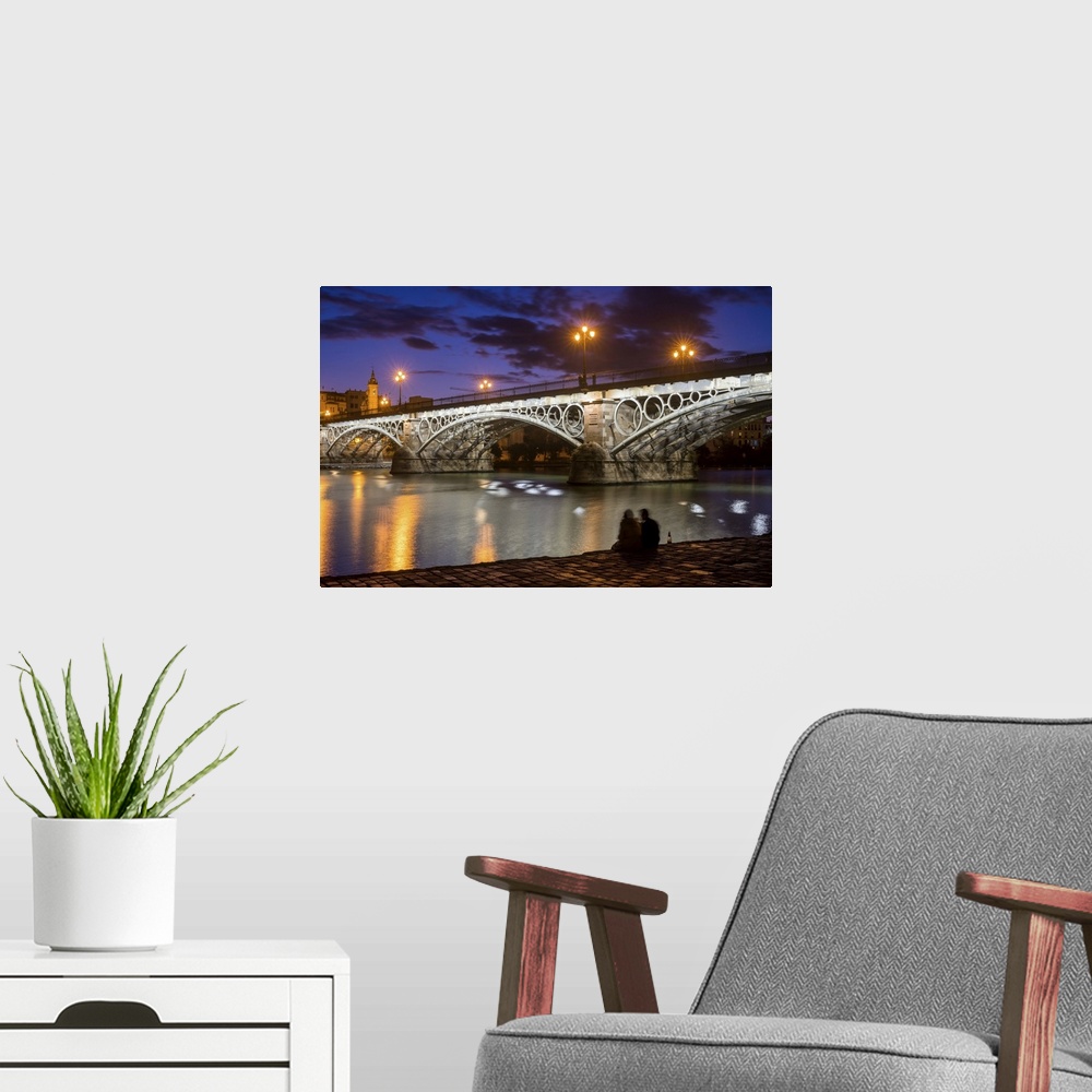 A modern room featuring Young couple drinking sparkling wine by the Guadalquivir river and the Triana bridge in Seville, ...