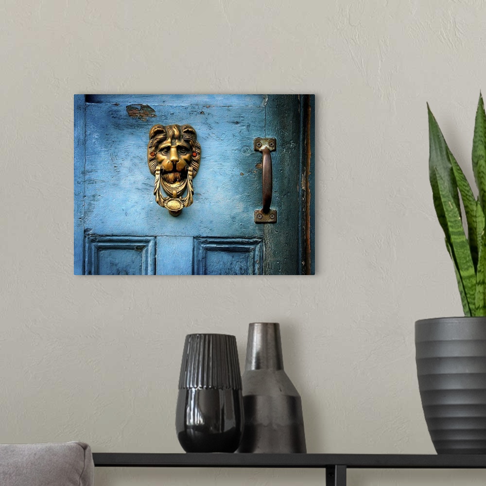 A modern room featuring A brass door knocker on a blue door in the shape of a lions head