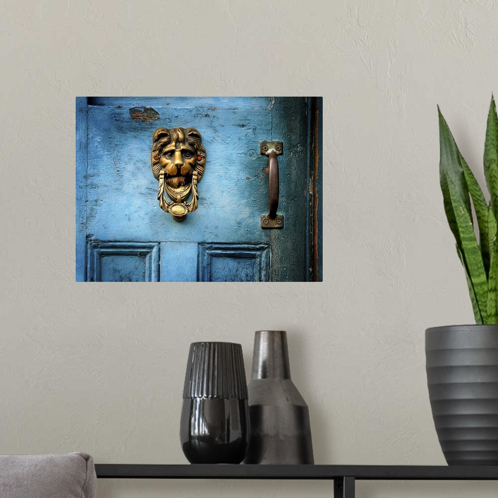 A modern room featuring A brass door knocker on a blue door in the shape of a lions head