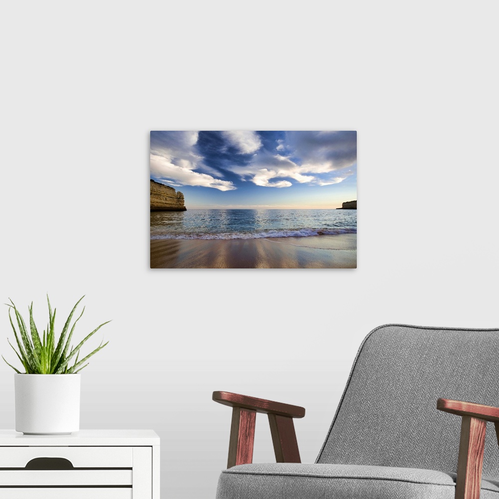 A modern room featuring A beautiful picture taken while standing on a beach and looking out at the vast ocean. Cliffs lin...