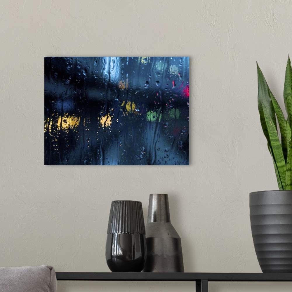 A modern room featuring A rain strreaked window with blurred city lights.