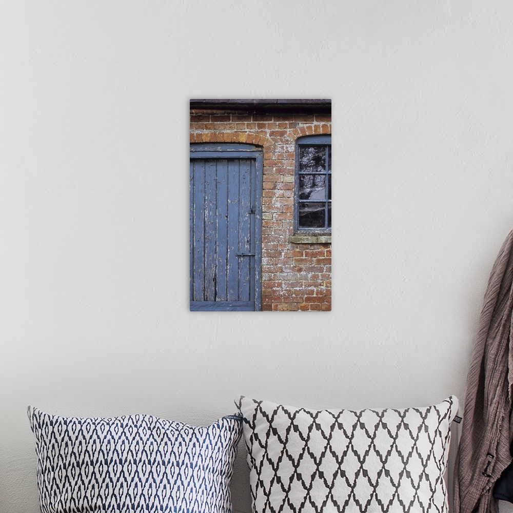 A bohemian room featuring Detail of old orange brick stable block or barn with flaking blue painted wooden door and windows...