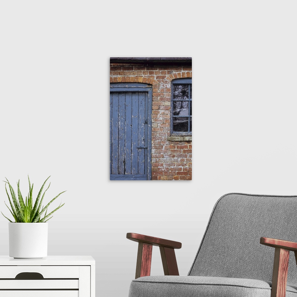 A modern room featuring Detail of old orange brick stable block or barn with flaking blue painted wooden door and windows...