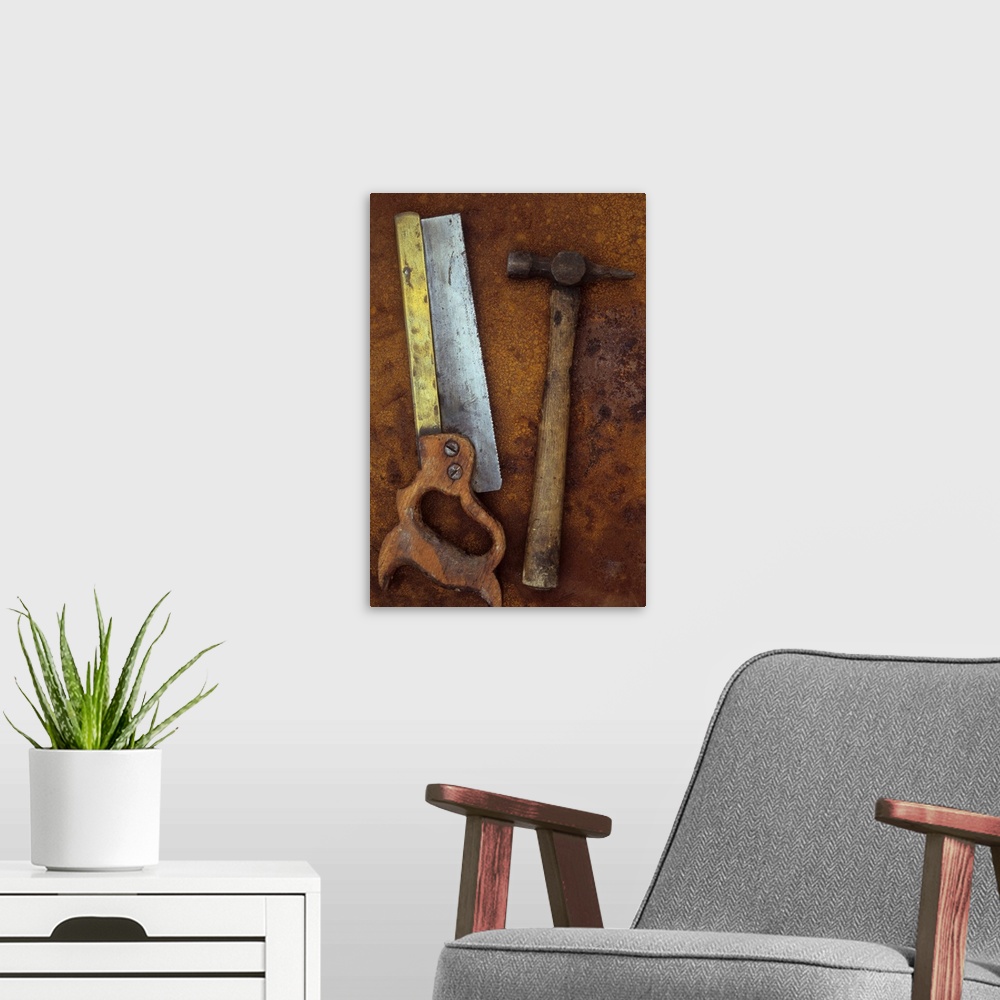 A modern room featuring Old well-used tenon saw with wooden handle and brass stiffening bar lying with hammer on rusty me...