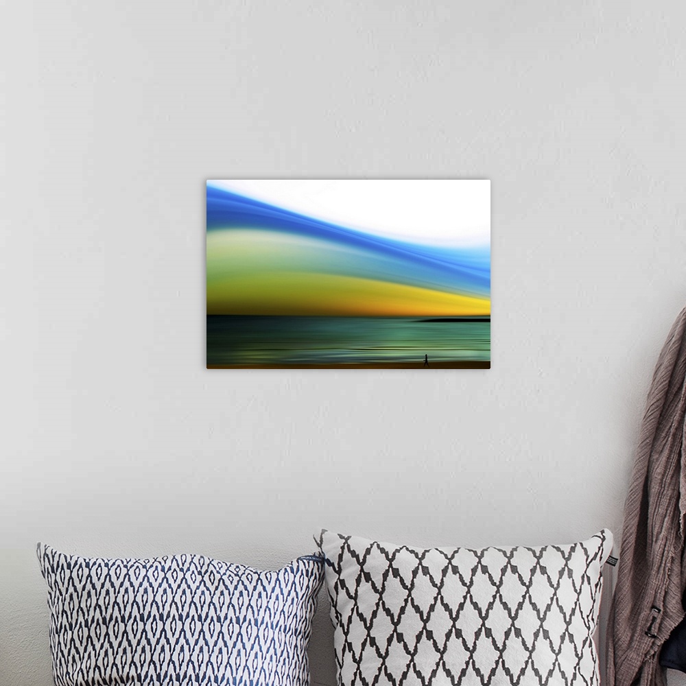 A bohemian room featuring Wall art of a person's silhouette walking on the shore of a beach with an abstractly colored sky.
