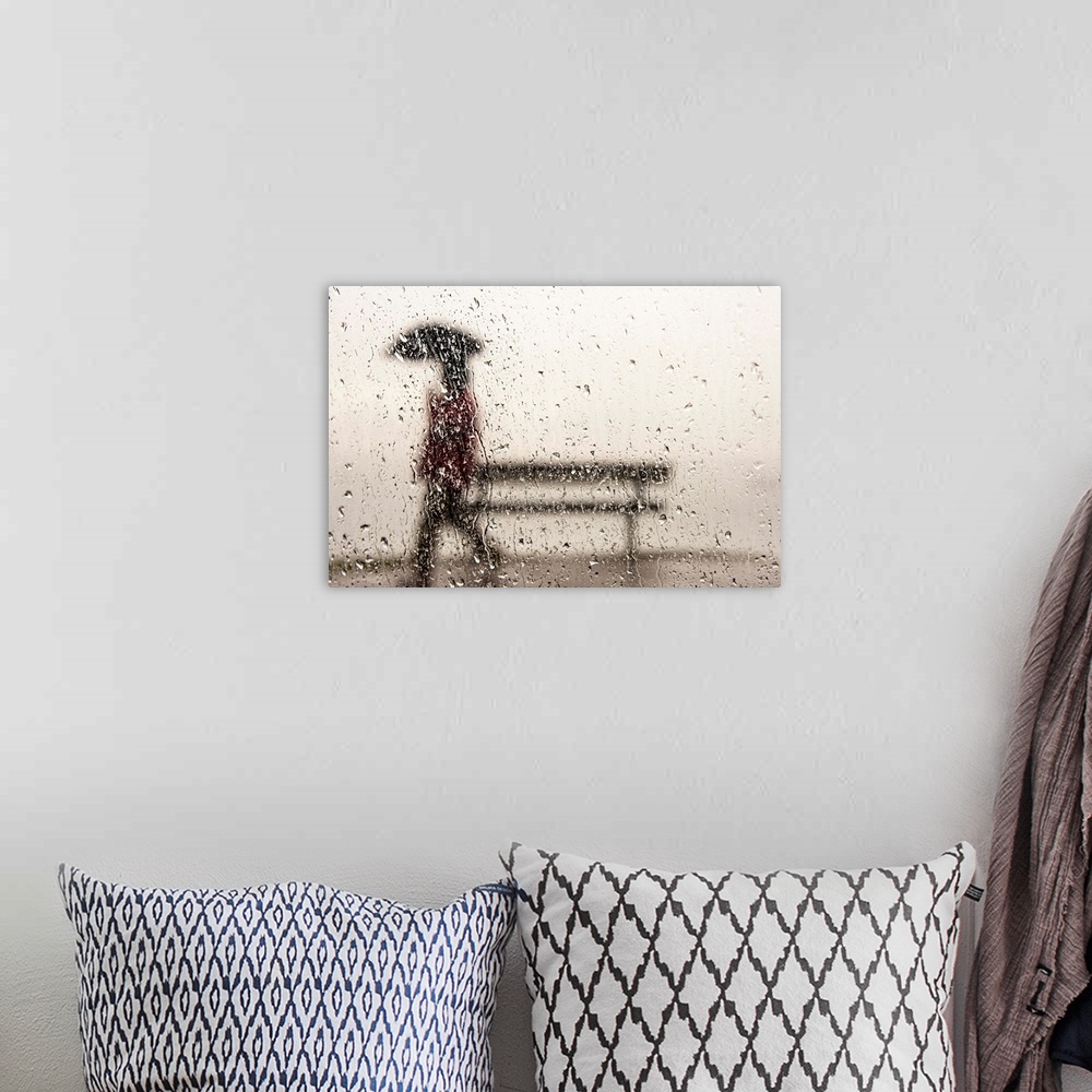 A bohemian room featuring A man walking with an umbrella against a rain streaked window.
