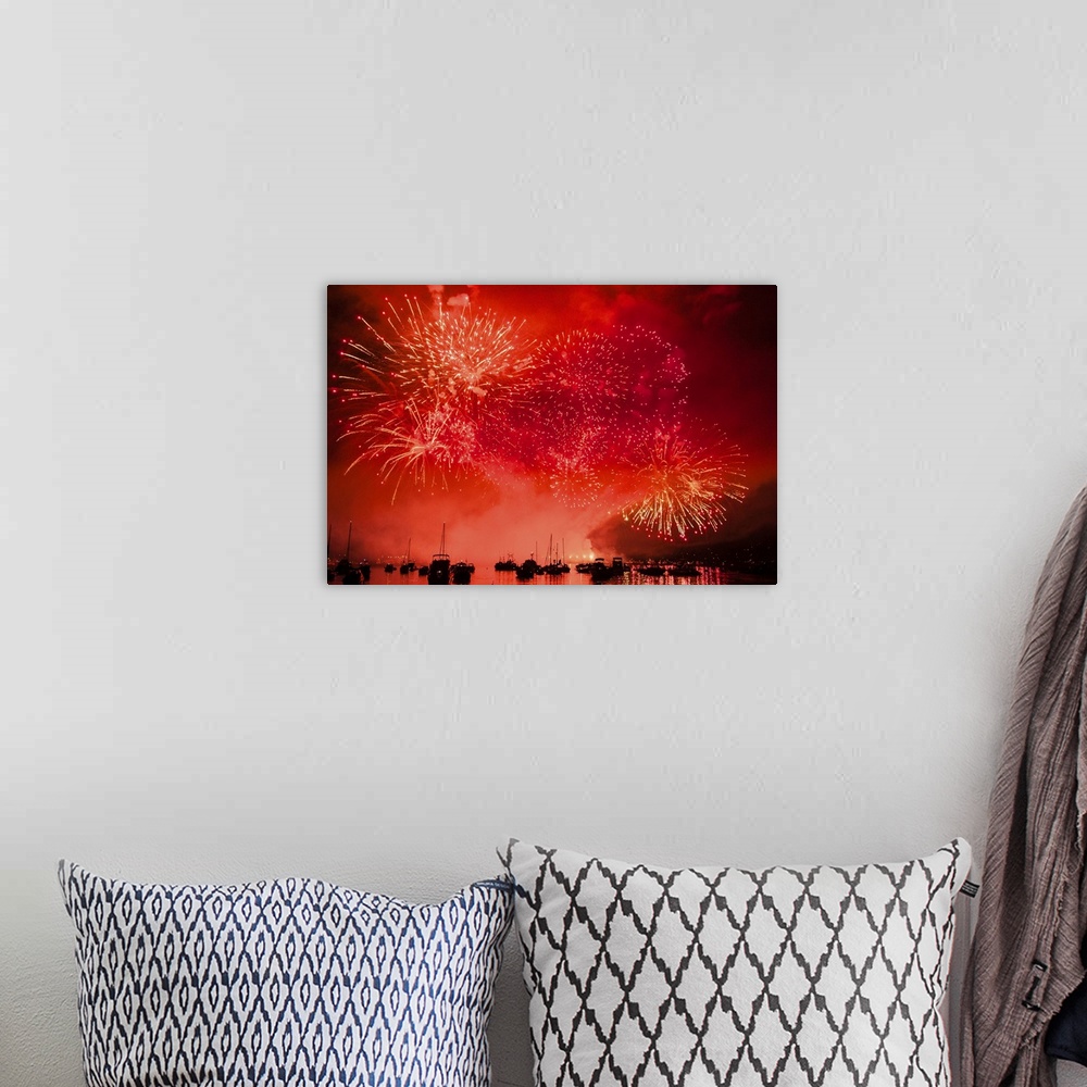 A bohemian room featuring Fireworks and boats in the ocean against a red sky