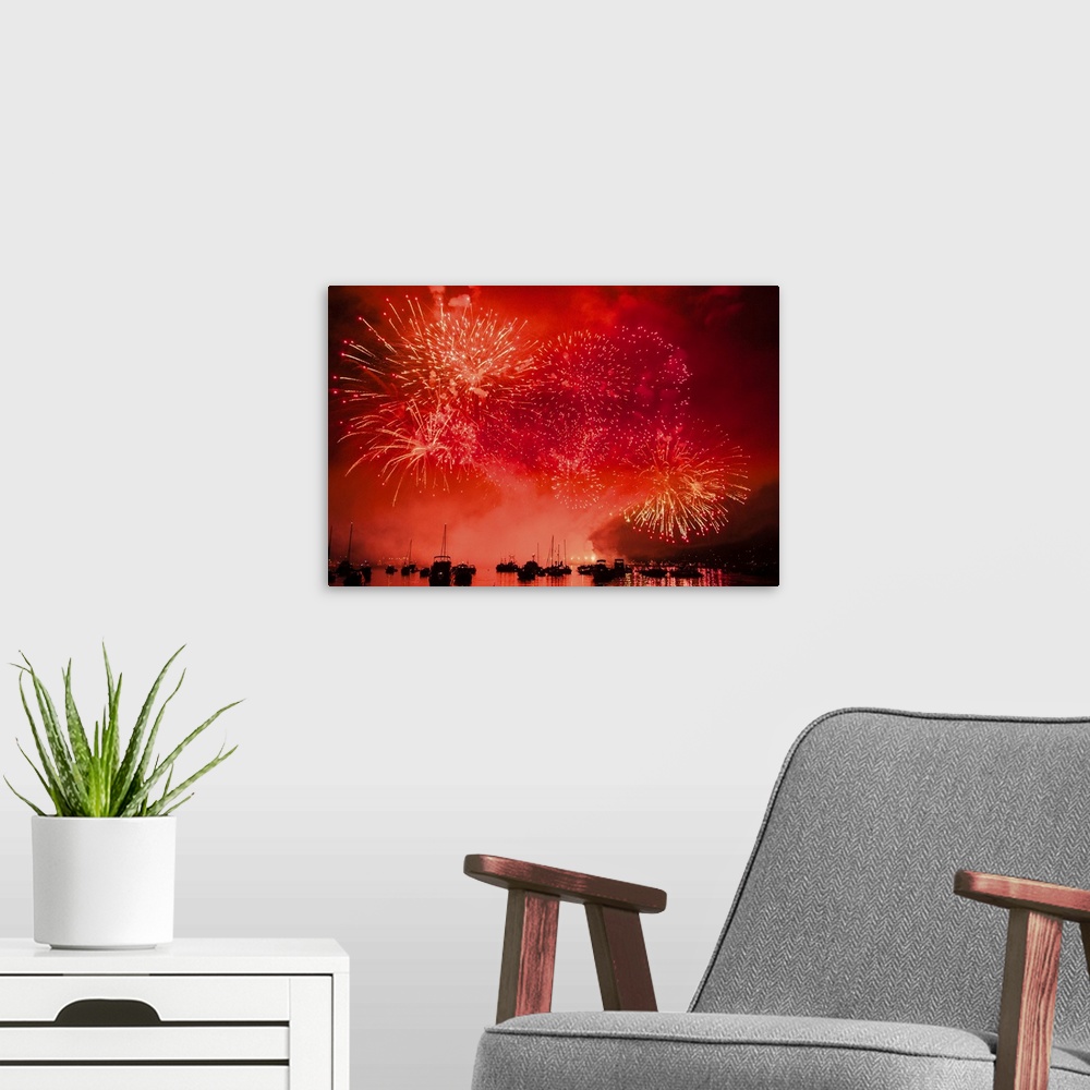 A modern room featuring Fireworks and boats in the ocean against a red sky