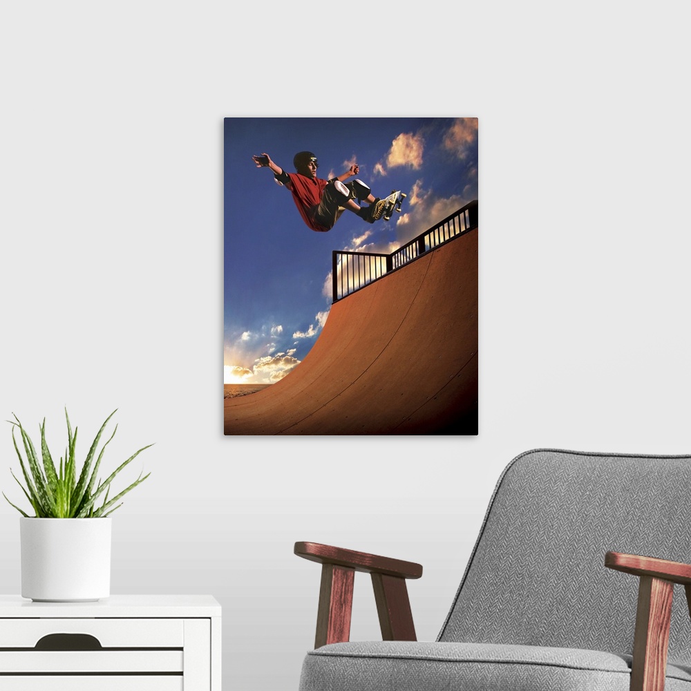 A modern room featuring A young boy gets air on his skateboard while skating on a mini ramp at sunset