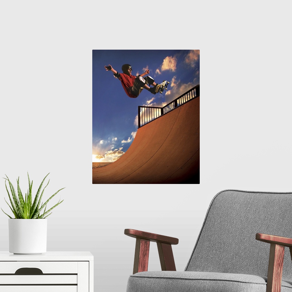 A modern room featuring A young boy gets air on his skateboard while skating on a mini ramp at sunset