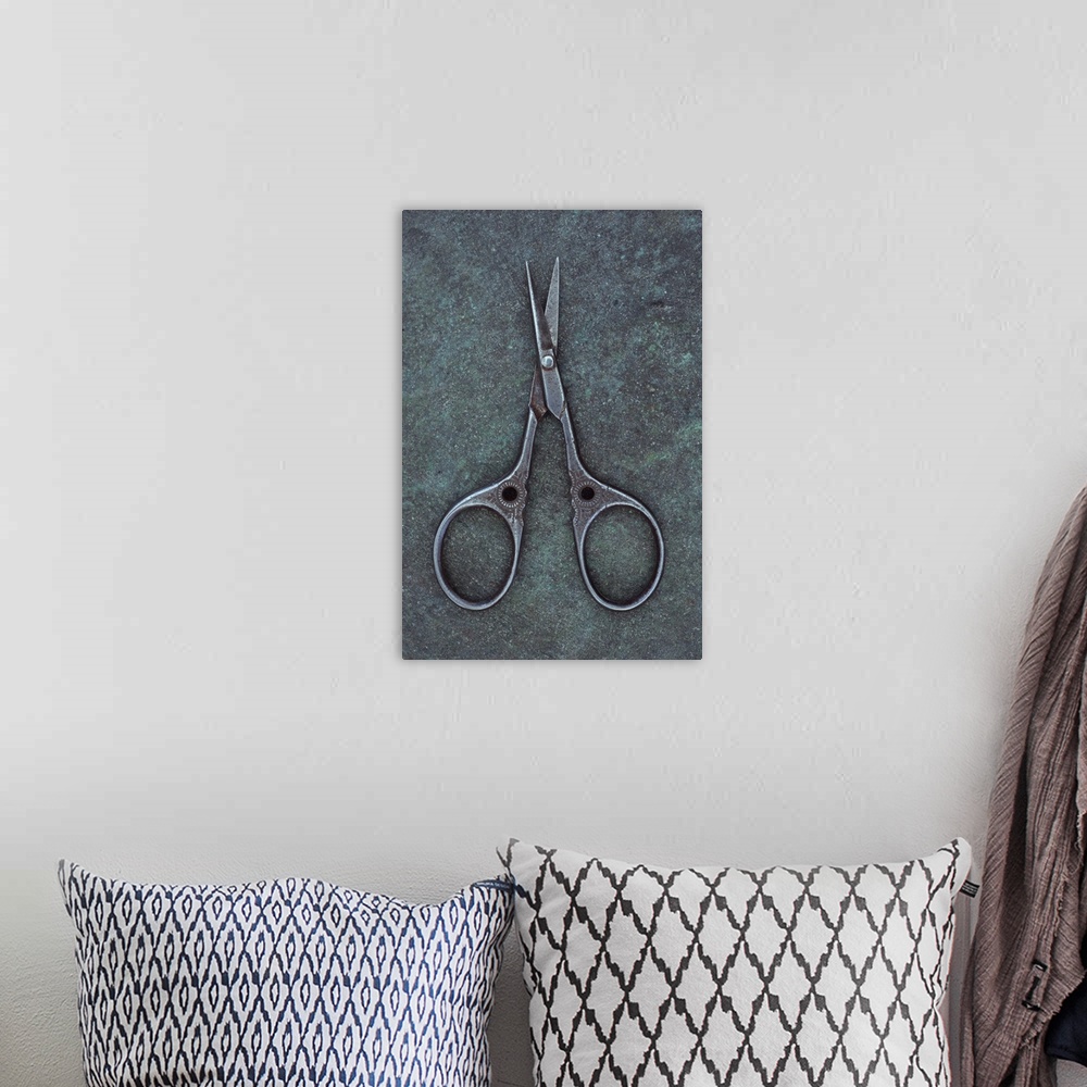 A bohemian room featuring Antique steel sewing scissors decorated with small pattern lying on tarnished metal
