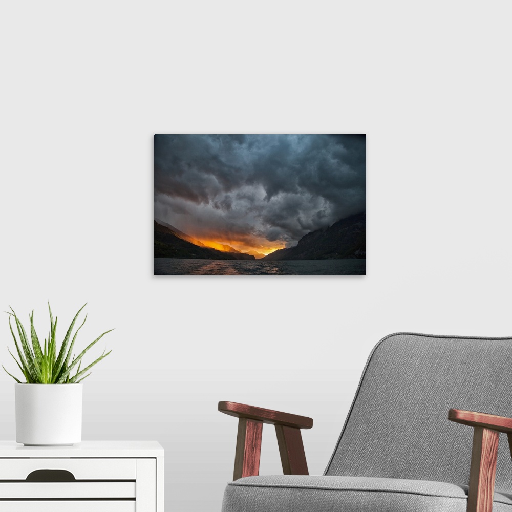 A modern room featuring Glowing sunrise/sunset with stormy sky over mountains