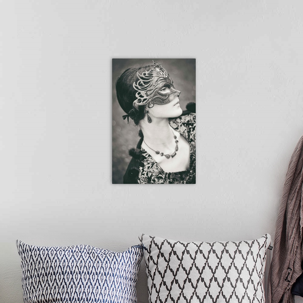 A bohemian room featuring Profile of victorian girl wearing carnival mask, looking down with sad emotion. Monochrome shot.