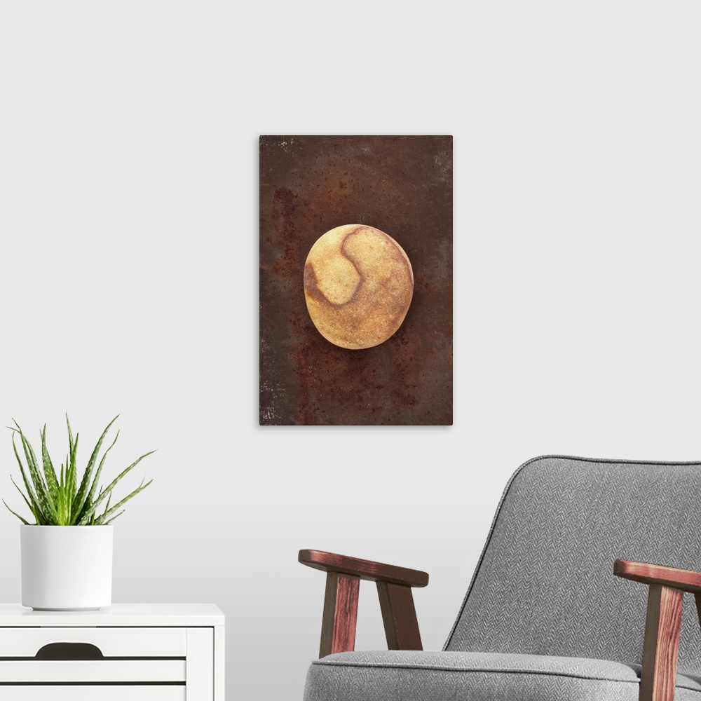 A modern room featuring Smooth brown pebble with markings resembling planet lying on rusty metal sheet