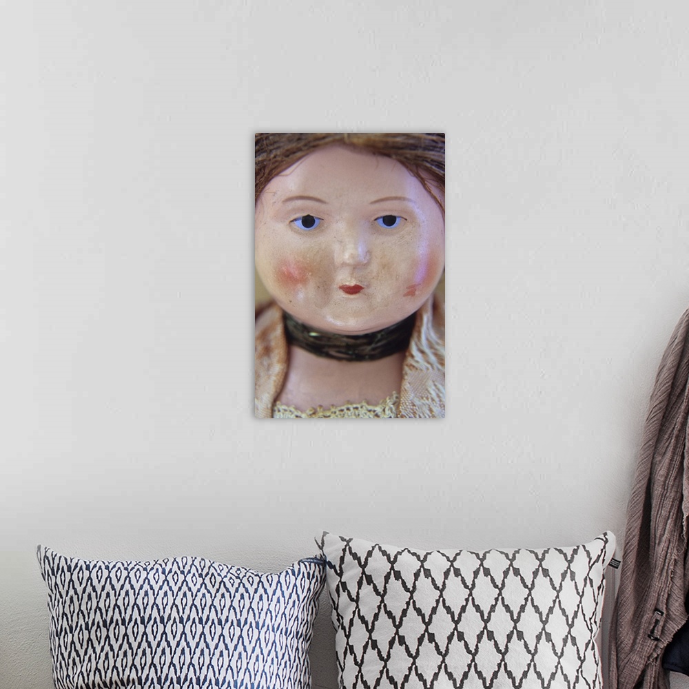 A bohemian room featuring Face of vintage woman doll with tight bun and glum face and wearing lacy clothes and neckband