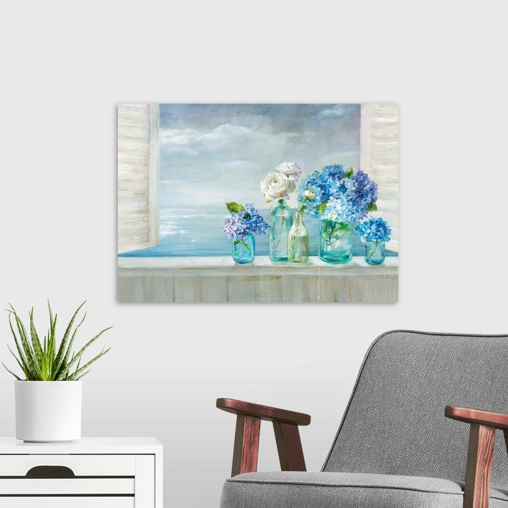 A modern room featuring A collection of flowers in blue glass vases on a windowsill overlooking the ocean.