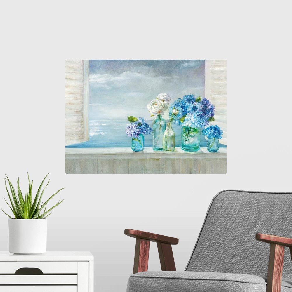 A modern room featuring A collection of flowers in blue glass vases on a windowsill overlooking the ocean.