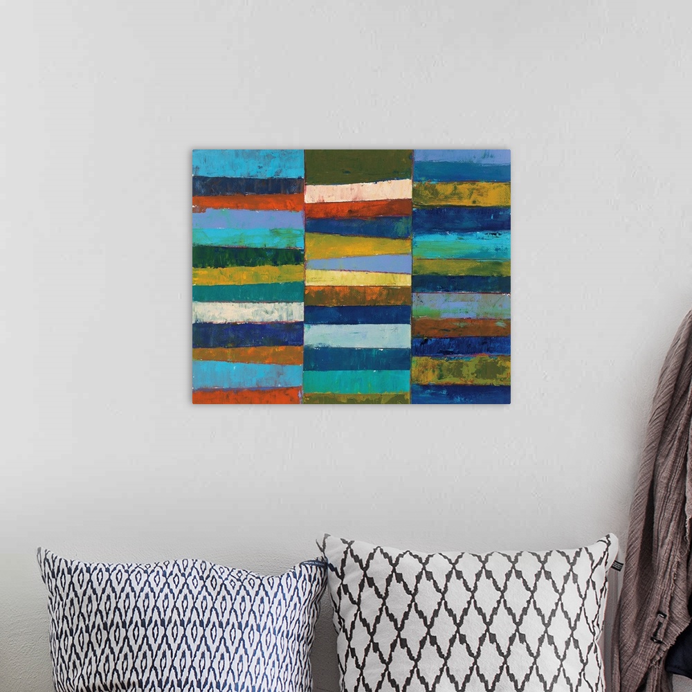 A bohemian room featuring A bright geometric abstract painting featuring blocks of color stacked in three columns. It has a...