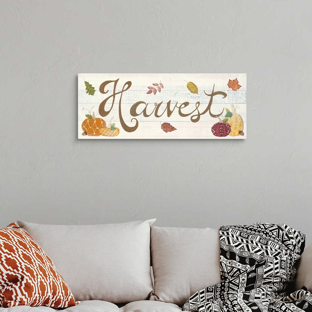 A bohemian room featuring Decorative artwork of the word "Harvest" with fall leaves and pumpkins and a white wood background.