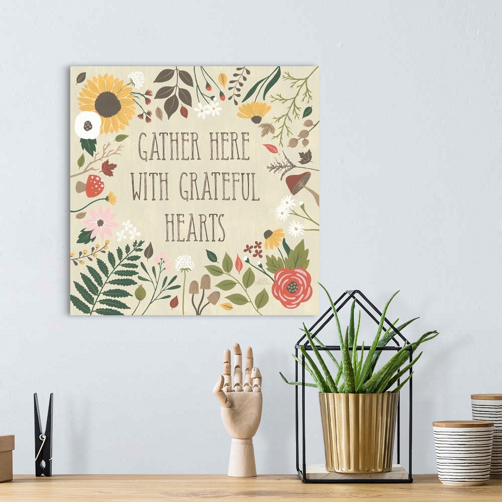 A bohemian room featuring "Gather here with grateful hearts" written on a tan background and surrounded by Autumn flowers.