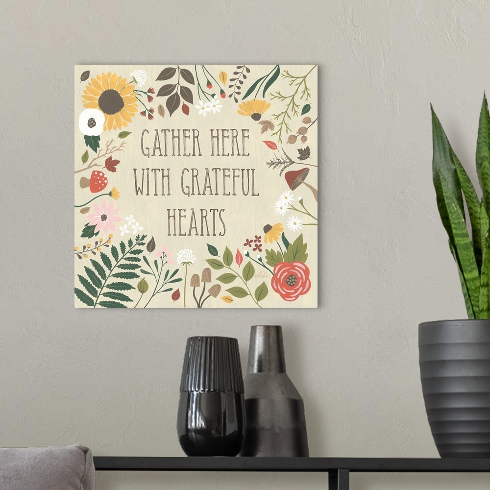A modern room featuring "Gather here with grateful hearts" written on a tan background and surrounded by Autumn flowers.
