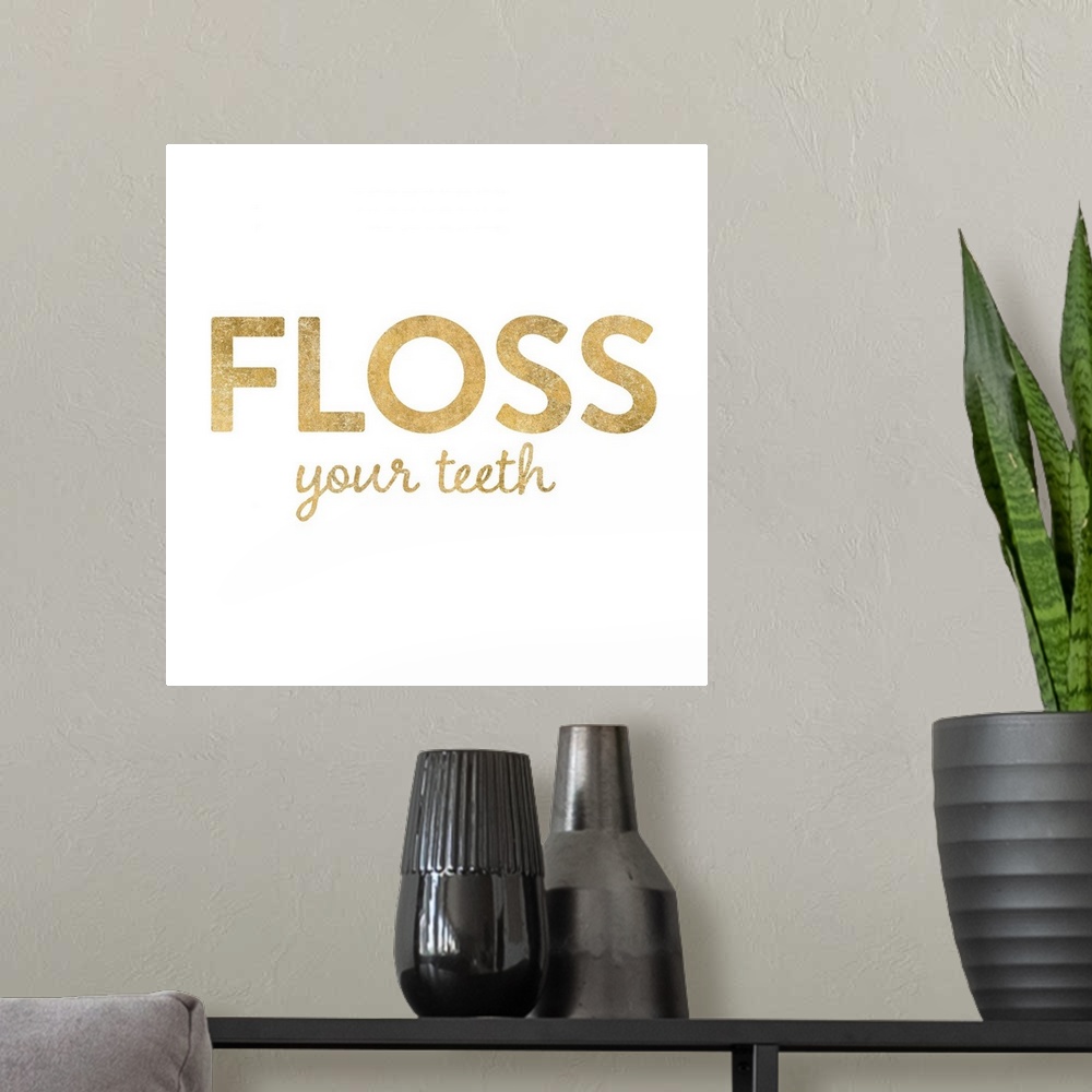 A modern room featuring "Floss Your Teeth" written in metallic gold on a solid white background.