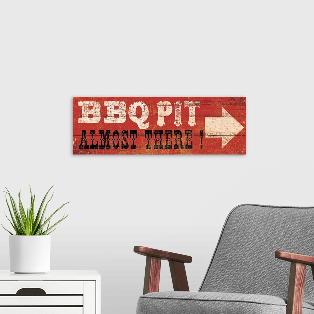 A modern room featuring This art piece resembles wood planks with an arrow and text painted saying BBQ Pit, Almost There.