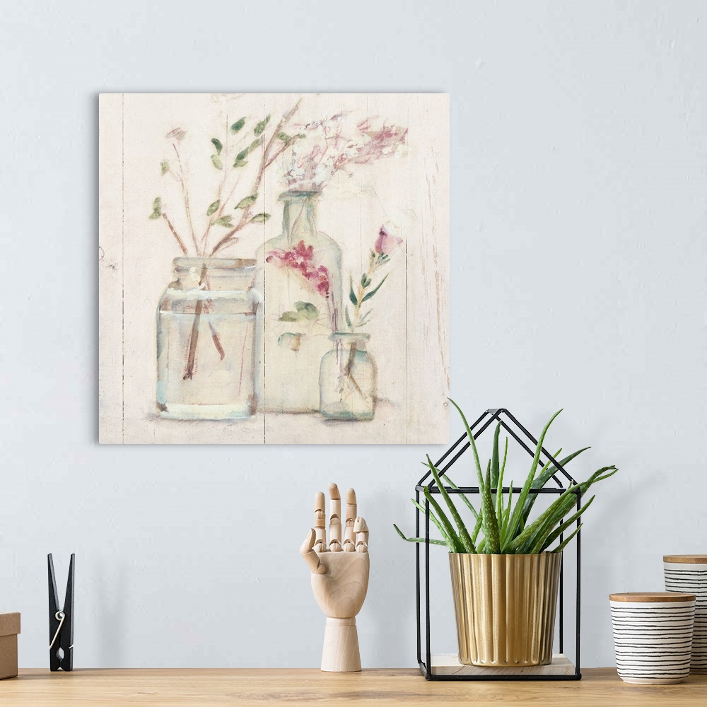 A bohemian room featuring Square artwork with flowers and branches in glass vases on a rustic shiplap background.