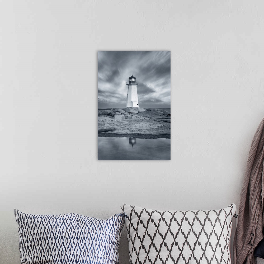 A bohemian room featuring A vertical black and white photograph of a white lighthouse reflecting in the water with a dramat...