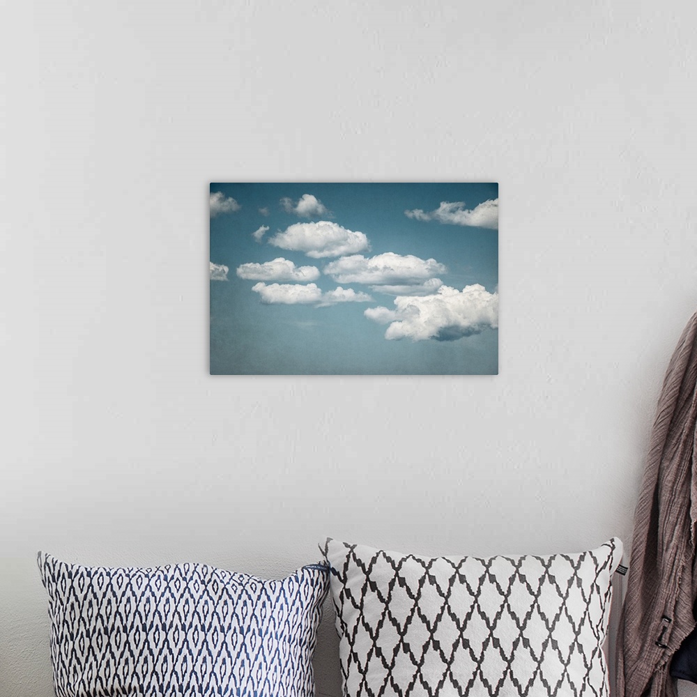 A bohemian room featuring A contemporary photograph of fluffy white clouds against a pale blue sky.