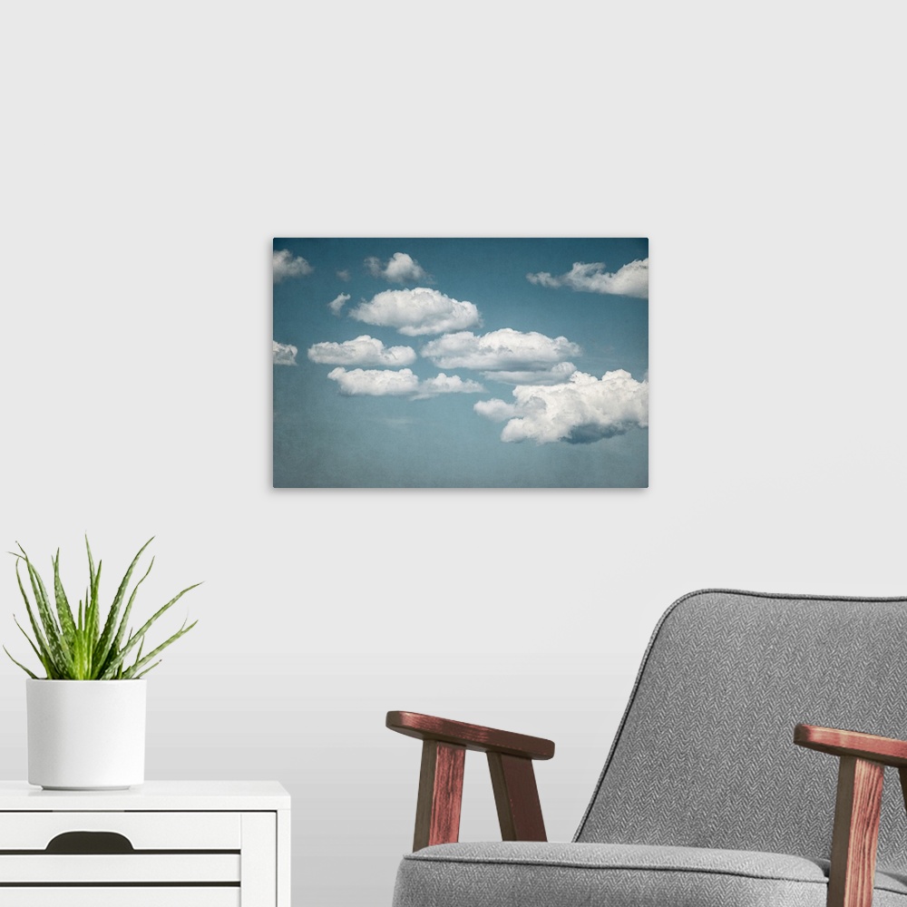 A modern room featuring A contemporary photograph of fluffy white clouds against a pale blue sky.