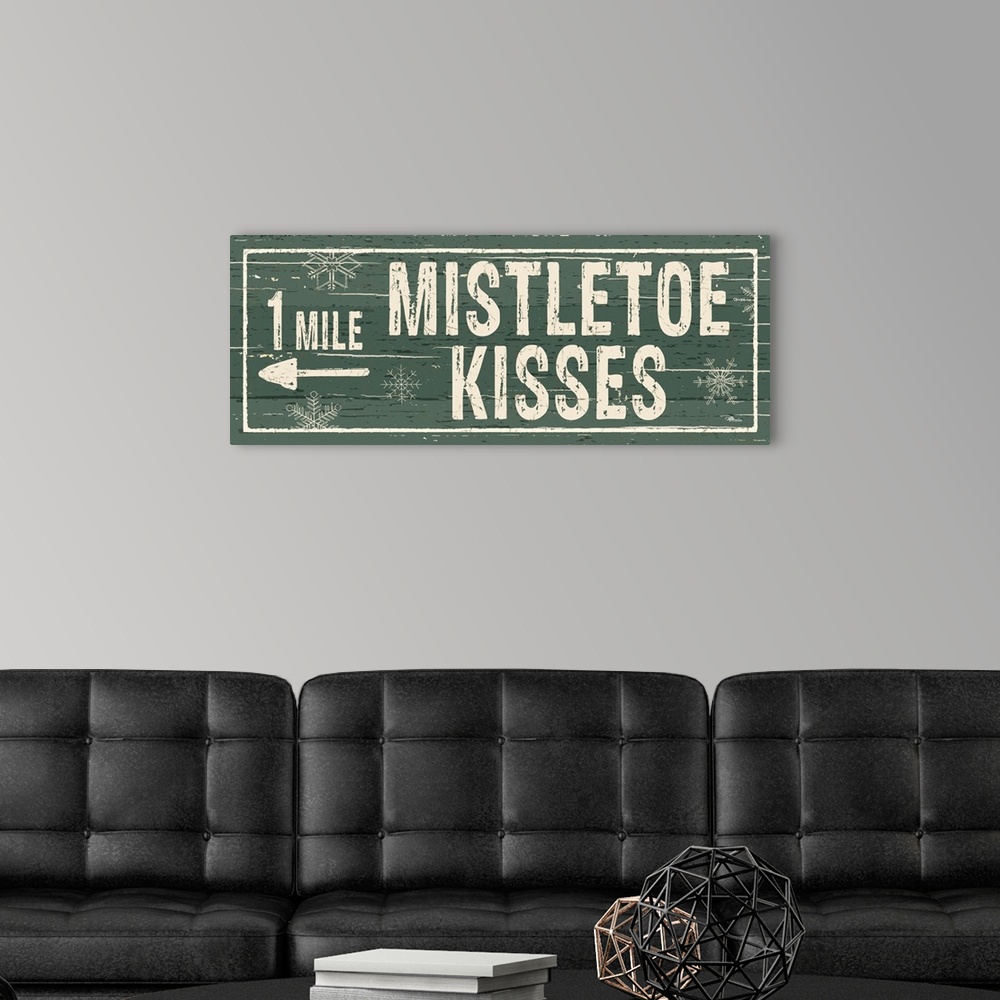 A modern room featuring Decorative artwork with a holiday theme with the text "1 Mile Mistletoe Kisses" on a green backdrop.
