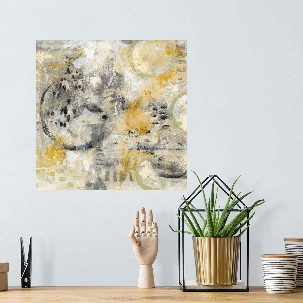 A bohemian room featuring Square abstract painting using gold, black, and grey hues with hidden circles sporadically around.