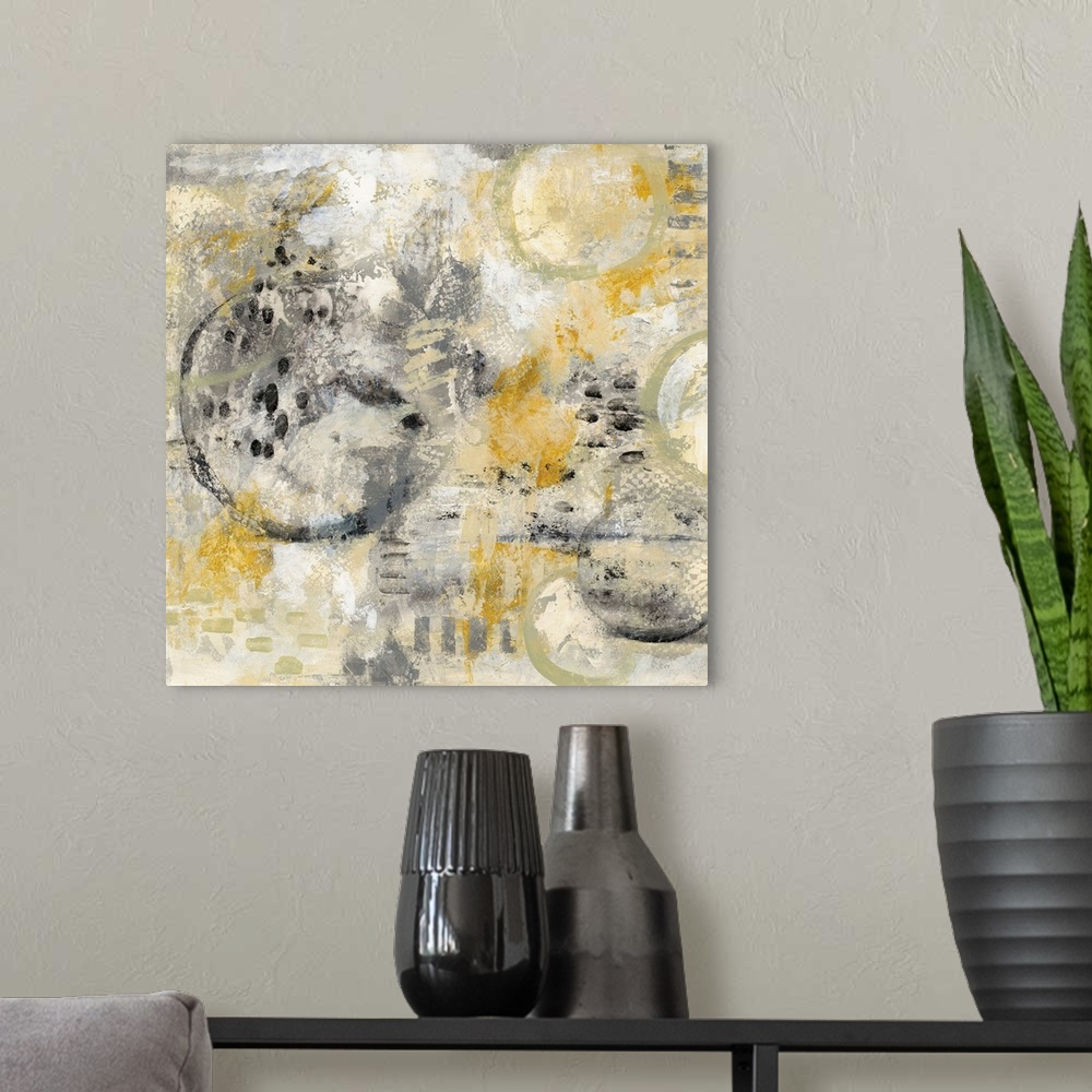 A modern room featuring Square abstract painting using gold, black, and grey hues with hidden circles sporadically around.