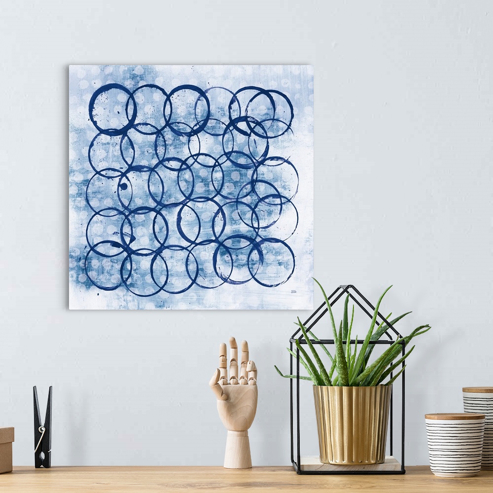 A bohemian room featuring Square abstract painting with indigo outlines of circles overlapping in the foreground and smalle...